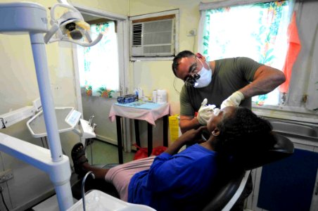 US Navy 090811-N-9689V-006 Cmdr. Dolph Garza a dentist, embarked aboard the Military Sealift Command dry cargo-ammunition ship USNS Richard E. Byrd (T-AKE 4) provides dental treatment to a patient