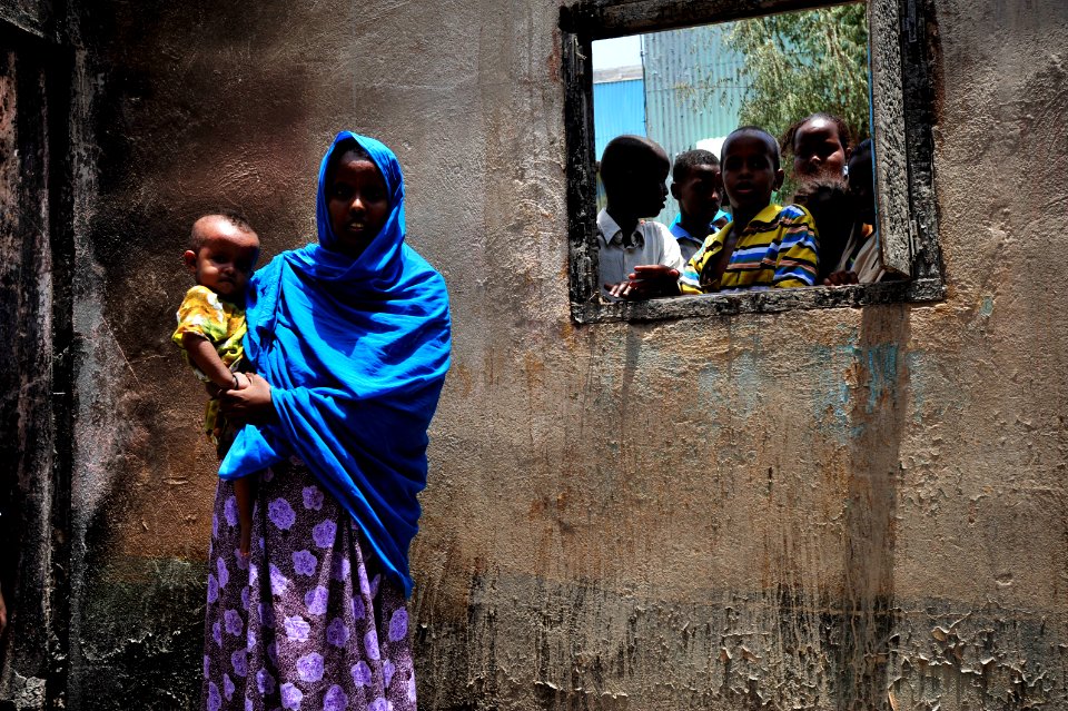 US Navy 090812-N-0506A-273 Zamzam Ahmed Dinbil stands holding her child in the burned remains of her home in Djibouti