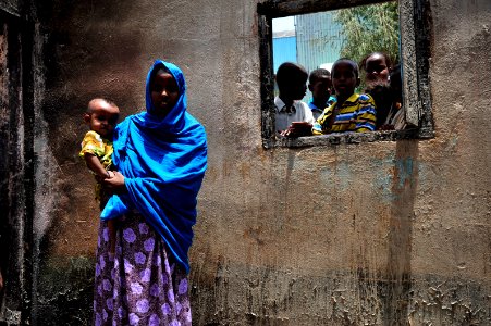 US Navy 090812-N-0506A-273 Zamzam Ahmed Dinbil stands holding her child in the burned remains of her home in Djibouti
