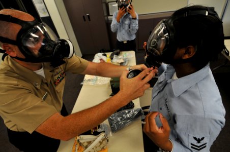 US Navy 090812-N-0807W-411 Hull Technician 1st Class Claude Lewis, chemical and biological Defense officer at Fleet Activities Sasebo, helps Quartermaster 2nd Class Alvera McKnight, from Covington, La., don her MCU-2P gas mask