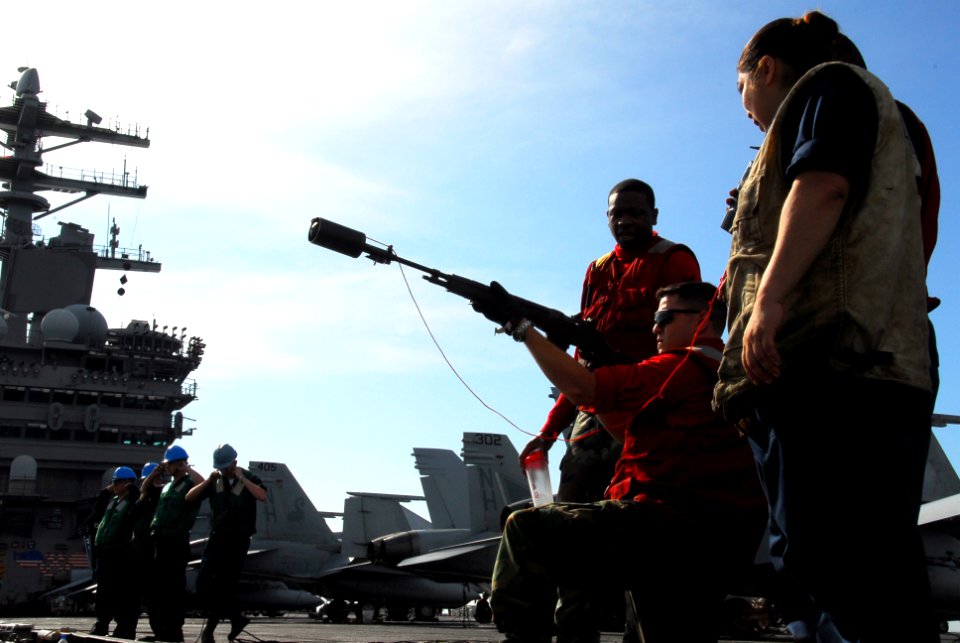 US Navy 090815-N-2918M-142 Aviation Ordnanceman Airman Steven King is supervised by Aviation Ordnanceman 2nd Class Curtis Pruitt as he aims a modified M14 rifle to launch a shot line during a replenishment at sea
