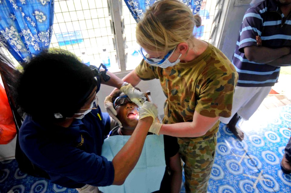US Navy 090811-N-9689V-007 Marie Williams, a dentist from the University of California, and dental hygienist Australian Army, Cpl. Diane Beningfield, provide dental treatment to a patient