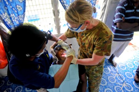 US Navy 090811-N-9689V-007 Marie Williams, a dentist from the University of California, and dental hygienist Australian Army, Cpl. Diane Beningfield, provide dental treatment to a patient