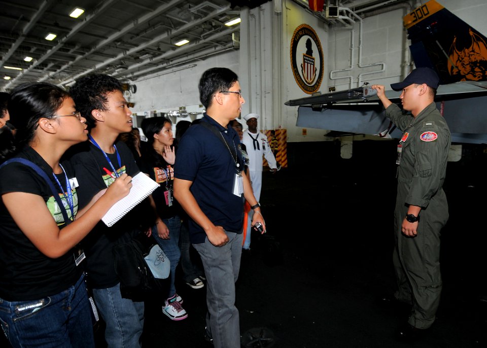 US Navy 090813-N-6233H-028 Lt. j.g. Kyler Chong, assigned to the Diamondbacks of Strike Fighter Squadron (VFA) 102, explains how an F-A 18C Hornet operates to students from Manila high schools