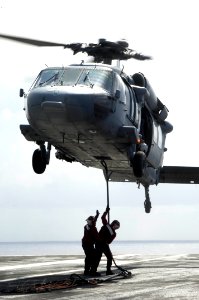 US Navy 090815-N-3038W-275 Sailors aboard the aircraft carrier USS Nimitz (CVN 68) hook up an ordnance canister to an MH-60S Sea Hawk helicopter assigned to the Wildcards of Helicopter Sea Combat Squadron (HSC 23) during an und