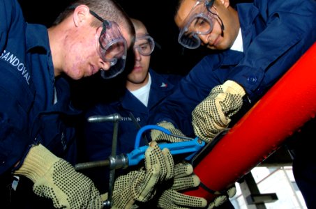US Navy 090818-N-4047W-016 Damage Controlman Fireman Ryan Sandoval, left, Information Systems Technician 3rd Class Scott Mortensen and Seaman Leroy Ramos practice pipe patching