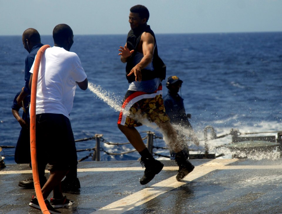 US Navy 090822-N-4879G-096 Hospital Corpsman 3rd Class Terrence Ash is sprayed by a hose during a freshwater wash down aboard the guided missile frigate USS Doyle (FFG 39)