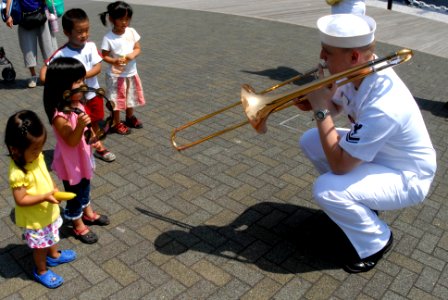 US Navy 090825-N-2600H-192 A Sailor assigned the U.S. 7th Fleet Band plays the trombone for children during a community service project to restore the historic Japanese battleship Mikasa photo