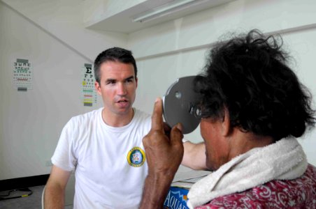 US Navy 090826-N-9689V-011 t. James David, an optometrist working with the Pacific Partnership 2009 mission, conducts an eye exam at Betio Sports Complex during a medical civic action project photo