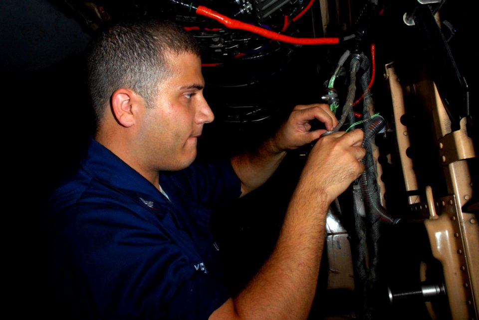 US Navy 090829-N-2600H-005 Aviation Electrician's Mate 3rd Class Patrick Oxendine, assigned to the Sidewinders of Strike Fighter Squadron (VFA) 86, troubleshoots an electrical connection on the undercarriage of a F-A-18C Hornet