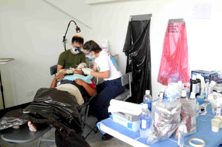 US Navy 090826-N-9689V-012 Canadian Army Capt. Jason Yee and Hospital Corpsman 3rd Class Angel Herndon provide dental treatment to a local woman at Betio Sports Complex, during a Pacific Partnership 2009 medical civic action pr photo