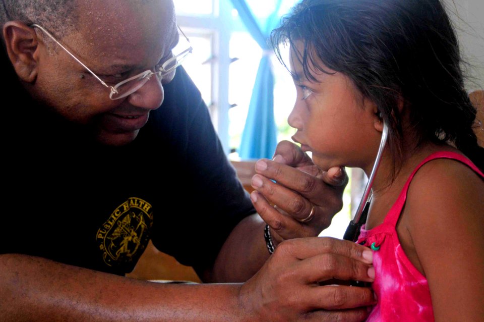 US Navy 090829-N-9689V-004 U.S. Public Health Service oncologist Capt. Otis Brawley allows a child to listen to her own breathing during a Pacific Partnership 2009 medical civic action project