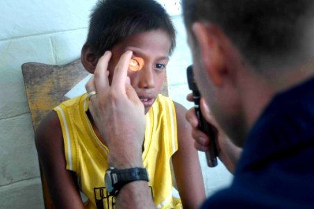 US Navy 090829-N-9689V-003 Navy optometrist Lt. James David examines a child during a Pacific Partnership 2009 medical civic action project photo