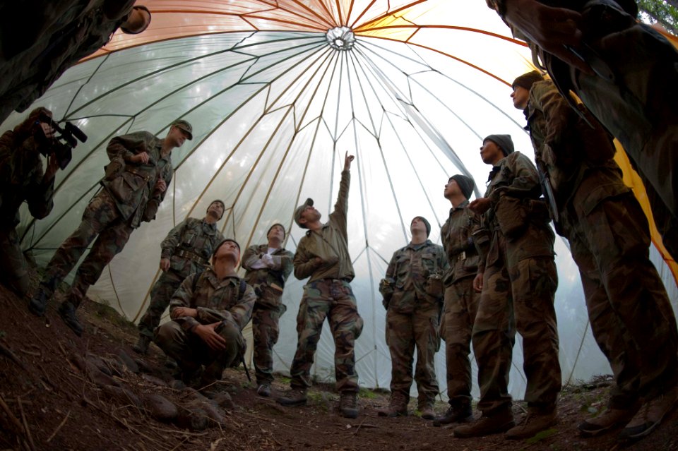 US Navy 090826-O-1234S-035 Center for Security Forces instructor Gerald Fine, center, instructs members from the 2009 class of NASA astronaut candidates on the uses of a parachute canopy for shelter during a week of survival tr