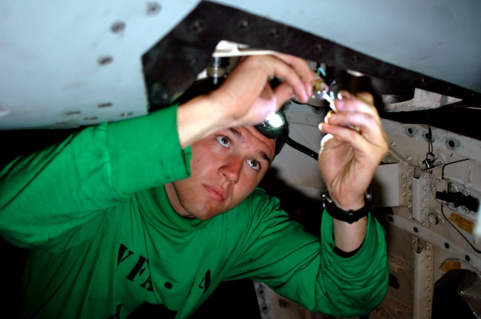 US Navy 090901-N-8960W-030 Aviation Boatswain's Mate Electricial Airman Christopher Baker wires on a F-A-18E Super Hornet assigned to the Tophatters of Strike Fighter Squadron (VFA) 14 aboard the aircraft carrier USS Nimitz (CV