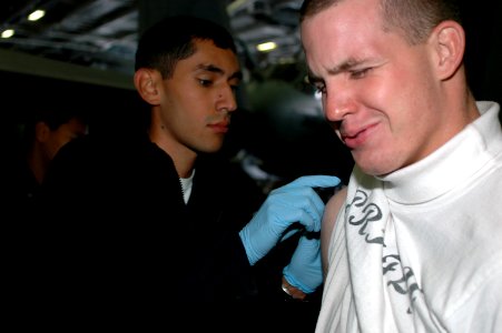 US Navy 090901-N-8960W-023 Aviation Boatswain's Mate Airman Kyle Hester winces as he receives his smallpox vaccine from Hospital Corpsman 3rd Class Matthew Quiantana aboard the aircraft carrier USS Nimitz (CVN 68)