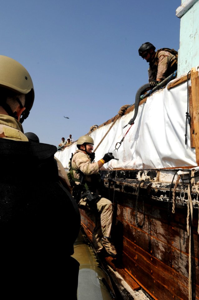 US Navy 090908-N-6814F-074 An NCIS Special Agent climbs a caving ladder to board a dhow for questioning, near the guided-missile cruiser USS Anzio (CG 68)