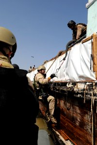 US Navy 090908-N-6814F-074 An NCIS Special Agent climbs a caving ladder to board a dhow for questioning, near the guided-missile cruiser USS Anzio (CG 68)
