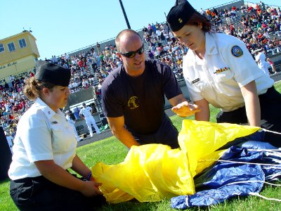 US Navy 090902-N-2888Q-072 ames Woods, center, a retired Navy SEAL and safety officer with the U.S. Navy parachute team, the Leap Frogs, shows Navy Junior ROTC cadets from Franklin Heights High School how to pack a parachute photo