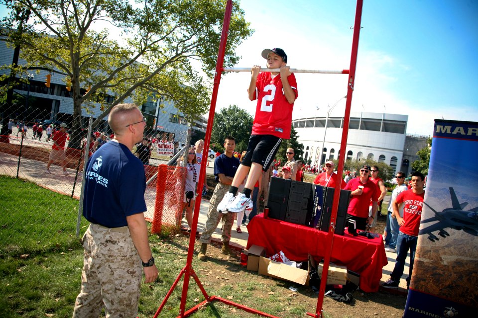 US Navy 090905-N-3271W-129 A young Buckeyes fan demonstrates his chin-up skills at a U.S. Marine Corps display alongside the Navy's F-A-18 Hornet flight simulator before the U.S. Naval Academy and Ohio State University football