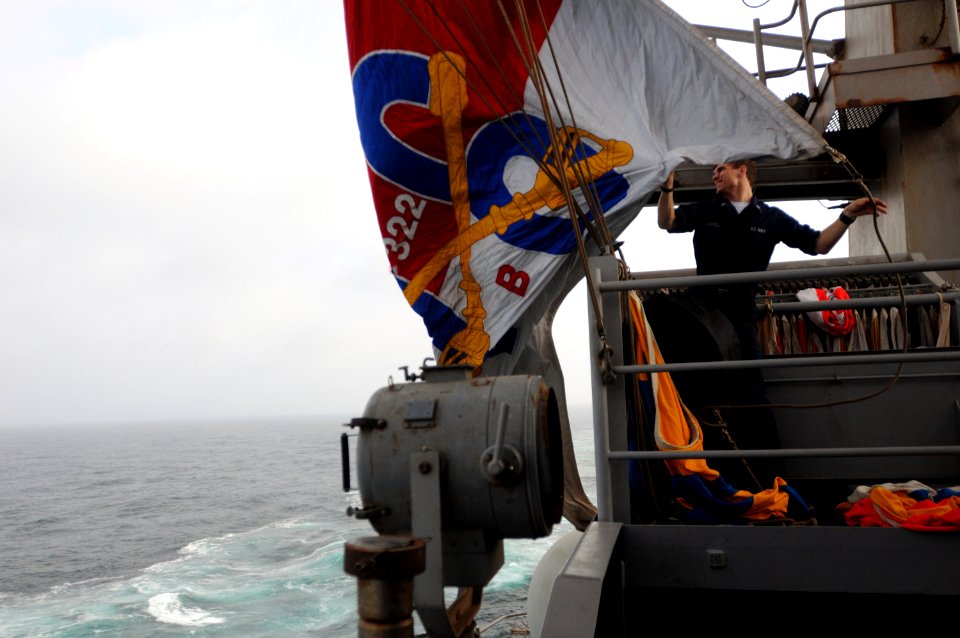 US Navy 090906-N-4995K-229 Quartermaster 3rd Class Christopher Campbell lowers the battle flag aboard the aircraft carrier USS Ronald Reagan (CVN 76) after a fueling at sea with the Arleigh Burke-class guided-missile destroyer