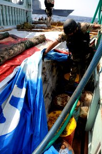US Navy 090908-N-6814F-097 The visit, board, search, and seizure team members check cargo during a boarding operation aboard a dhow near the guided-missile cruiser USS Anzio (CG 68)