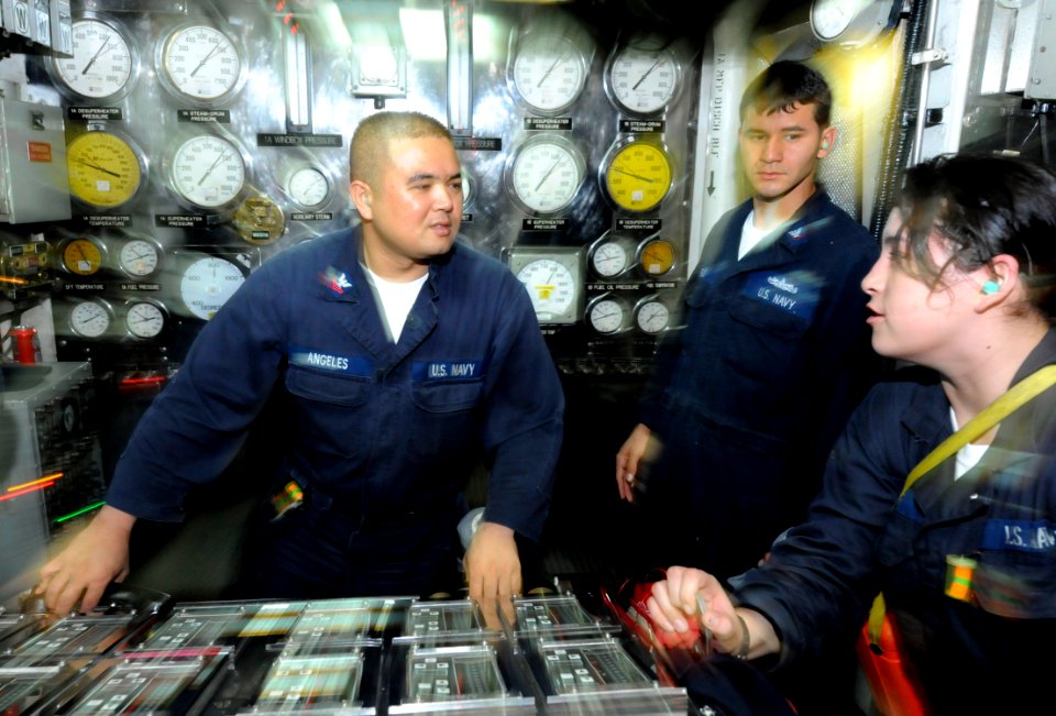 US Navy 090909-N-7280V-247 Machinist's Mate 2nd Class Pierre Angeles, a boiler technician of the watch (BTW), receives a report from Machinist's Mate Fireman Bianca Cruz