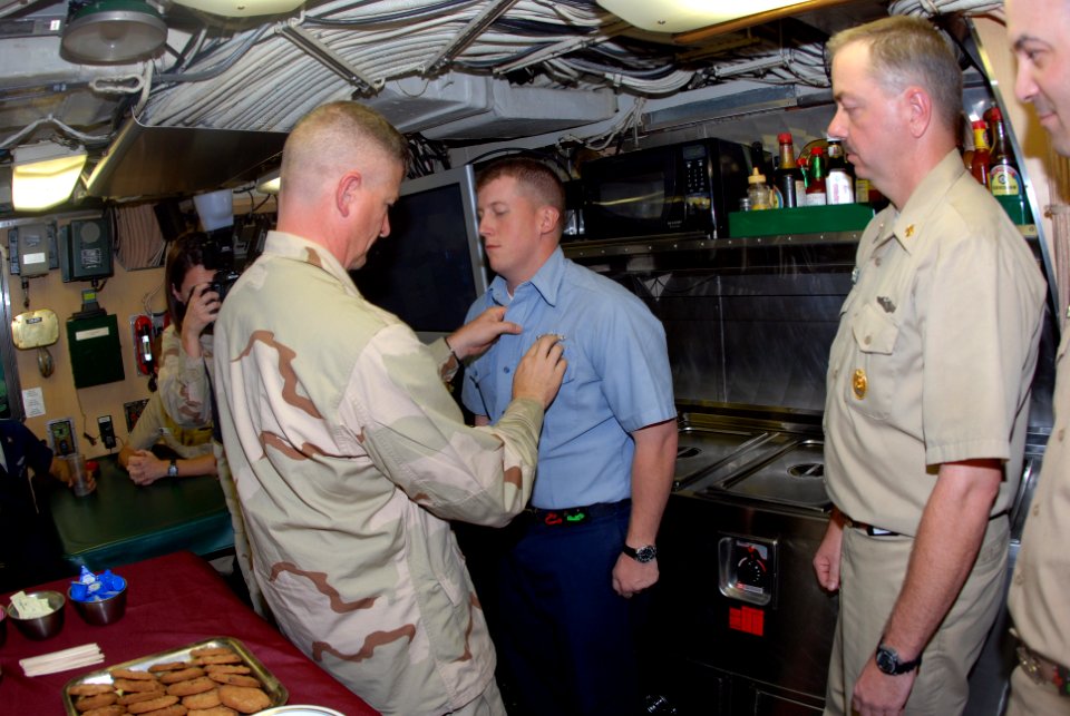 US Navy 090911-N-0803S-017 Master Chief Petty Officer of the Navy (MCPON) Rick West pins a submarine warfare qualification insignia on Machinist's Mate Seaman Shannon Coon