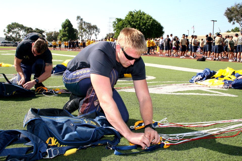 US Navy 090909-N-5366K-017 Special Warfare Operator 1st Class (SEAL) Isaiah Maring, assigned to the U.S. Navy demonstration parachute team, the Leap Frogs, packs his parachute after jumping during the opening ceremony of the PO