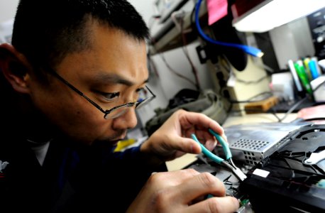 US Navy 090911-N-7280V-541 Electronics Technician 2nd Class Tony Yeh works on a computer drive in the micro miniature electronics lab aboard the amphibious command ship USS Blue Ridge (LCC 19) photo