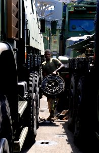 US Navy 090914-N-5345W-168 A Marine assigned to the 22nd Marine Expeditionary Unit (22nd MEU) carries a spool of cable between rows of medium tactical vehicle replacements (MTVR) during an equipment inventory aboard the amphibi