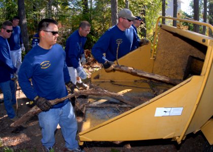 US Navy 090912-N-9860Y-005 chief petty officer selects feed logs and brush into a wood chipper