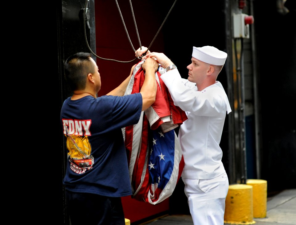 US Navy 090912-N-0413R-370 Intelligence Technician 2nd Class James Alcorn and New York City fireman Henry Gullotti raise colors over the fire station of Engine 8, Ladder 2, 8th Battalion in New York