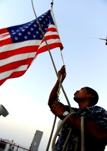 US Navy 090912-N-5345W-054 Boatswain's Mate Seaman D'angelo Robinson-Towns lowers the American flag during evening colors aboard the amphibious dock landing ship USS Fort McHenry (LSD 43)