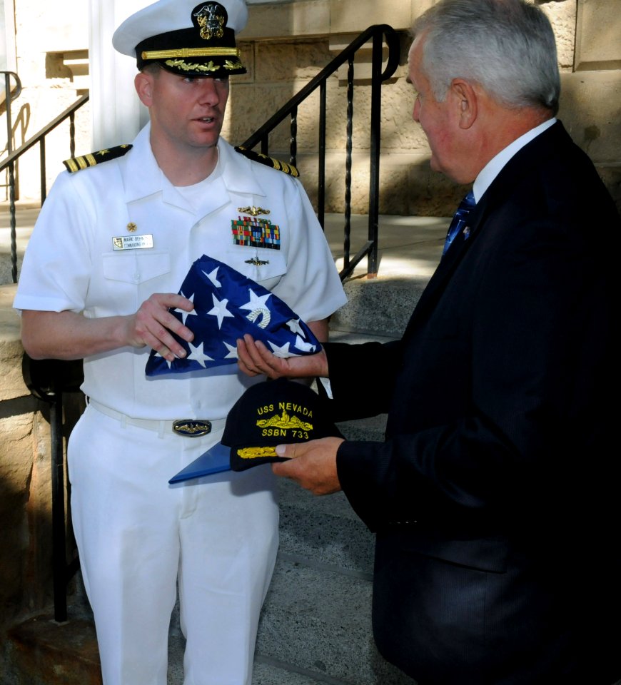 US Navy 090915-N-6220J-010 Commanding Officer of the Ohio-class fleet ballistic-missile submarine USS Nevada (SSBN 733) Cmdr. Marc Behning, presents an American flag flown on Sept. 11 aboard the USS Nevada, to Nevada Gov. Jim G