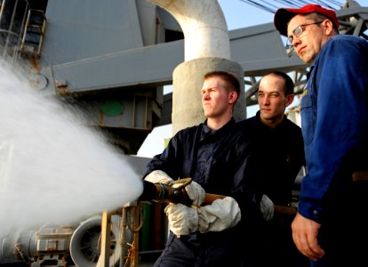 US Navy 090914-N-5345W-263 Chief Damage Controlman Donald Grothe supervises Hull Maintenance Technician 3rd Class John South and Damage Controlman Fireman David Pritchard during a hose-handling training exercise