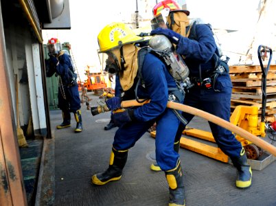 US Navy 090914-N-5345W-209 Fire team members begin to make their way into a smoke-filled boat deck space while responding to a simulated fire during a damage control drill aboard the amphibious dock landing ship USS Fort McHenr