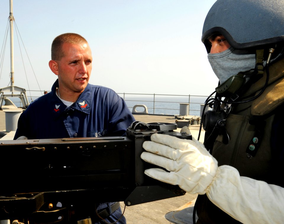 US Navy 090917-N-5345W-005 Gunner's Mate 2nd Class Michael Miller, left, goes over a training scenario with .50-caliber machine gun watchstander Boatswain's Mate 1st Class Israel Idrovo during a general quarters drill