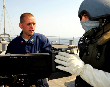 US Navy 090917-N-5345W-005 Gunner's Mate 2nd Class Michael Miller, left, goes over a training scenario with .50-caliber machine gun watchstander Boatswain's Mate 1st Class Israel Idrovo during a general quarters drill