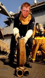 US Navy 090917-N-5345W-032 Hull Maintenance Technician 3rd Class John South secures emergency response equipment on the boat deck after a general quarters drill aboard the amphibious dock landing ship USS Fort McHenry (LSD 43)