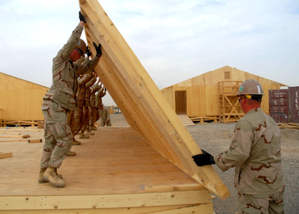 US Navy 090916-N-9564W-012 Seabees assigned to Naval Mobile Construction Battalion (NMCB) 74 raise a wall panel for a Southwest Asia hut