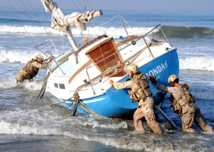US Navy 090917-N-1424C-384 Sailors assigned to Beach Master Unit (BMU) 1 move a beached sailboat into position to be salvaged off the military beach photo
