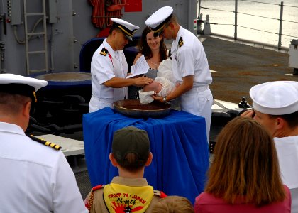US Navy 090917-N-6692A-047 Lt. John Madea holds his daughter as she is baptized with holy water from the ship's bell of the amphibious dock landing ship USS Tortuga (LSD 46)