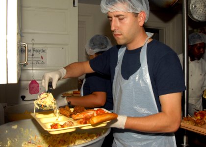 US Navy 090918-N-8560K-052 Machinist's Mate 2nd Class Brannon Kinsey, assigned to the aircraft carrier USS George H.W. Bush (CVN 77), adds coleslaw to a tray of food during a lunchtime meal at St. Vincent De Paul Catholic Church
