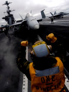 US Navy 090919-N-6538W-142 Aviation Boatswain's Mate (Handling) 3rd Class Gregory Scott, guides an F-A-18C Hornet onto catapult two during flight operations aboard the aircraft carrier USS John C. Stennis