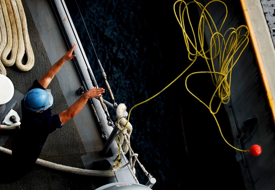 US Navy 090925-N-0807W-051 Seaman Nicholas S. Maloney heaves a messaging line to line-handlers on the pier as the amphibious dock landing ship USS Harpers Ferry (LSD 49) prepares to moor at White Beach Naval Facility
