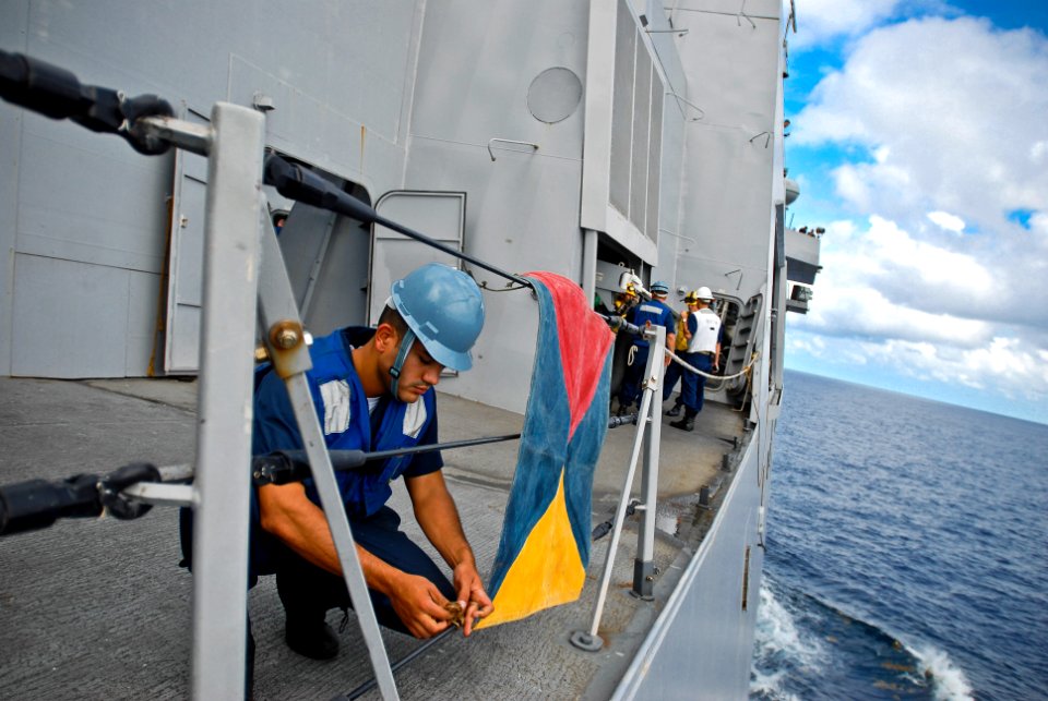US Navy 090919-N-8590G-008 Boatswains Mate 3rd Class Gabriel DeJesusortiz ties down the underway replenishment flag to prepare for a replenishment at sea with the Dutch navy fast combat support ship HNLMS Amsterdam (A836)