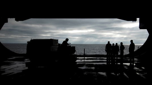 US Navy 090923-N-6538W-034 Sailors stand by as Aviation Boatswain's Mate (Handling) 3rd Class Jimmy Bergerson, from Modesto, Calif., operates a deck scrubber