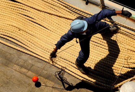 US Navy 090923-N-5345W-026 A deck department Sailor tosses a heaving line from the foc'sle of the amphibious dock landing ship USS Fort McHenry (LSD 43) as the ship moors pierside in Salalah, Oman, for a scheduled port visit