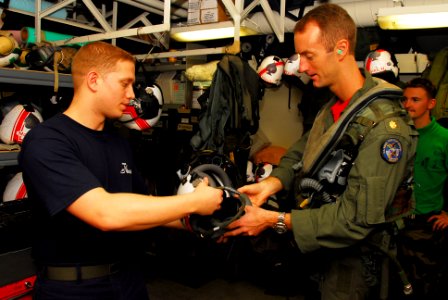 US Navy 090929-N-2918M-030 Aircrew Survival Equipmentman 2nd Class Steven Martin, left, hands Lt. Cmdr. Kevin McGee his flight helmet after a pre-flight inspection